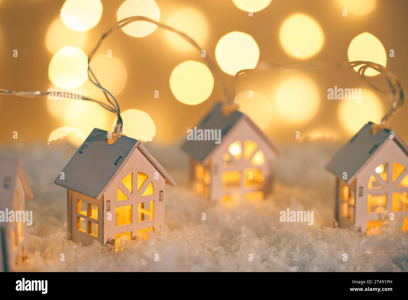 Case in legno, ghirlande di luci sulla neve e luci scintillanti su sfondo bokeh. Biglietto d'auguri per Natale e Capodanno con spazio per le copie. Illuminati per le vacanze Foto Stock