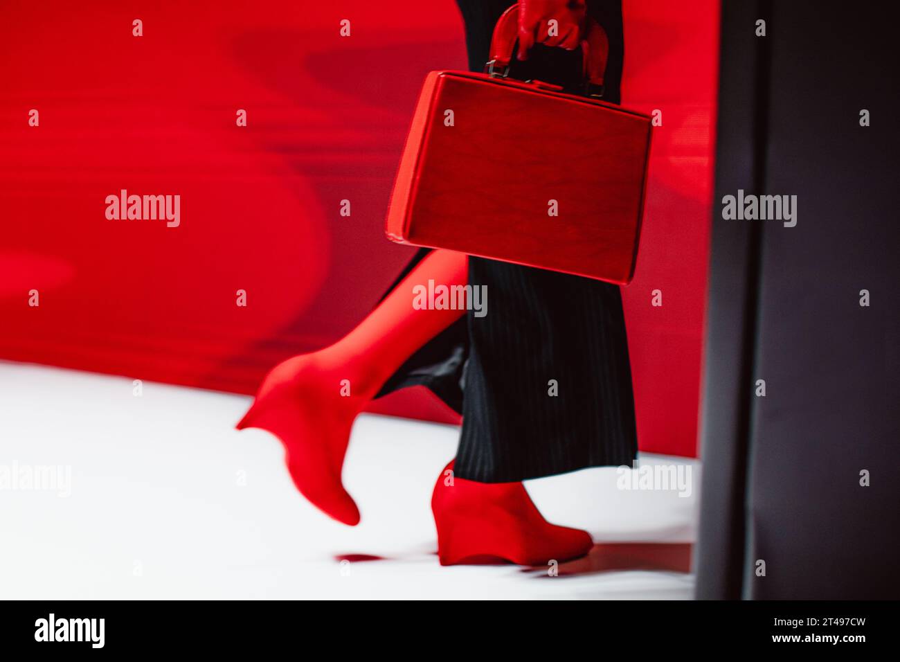 Dettagli alla moda: Gonna lunga nera, guanti rossi, borsa in pelle e tacchi alti. Modella di moda che cammina sulla passerella Foto Stock