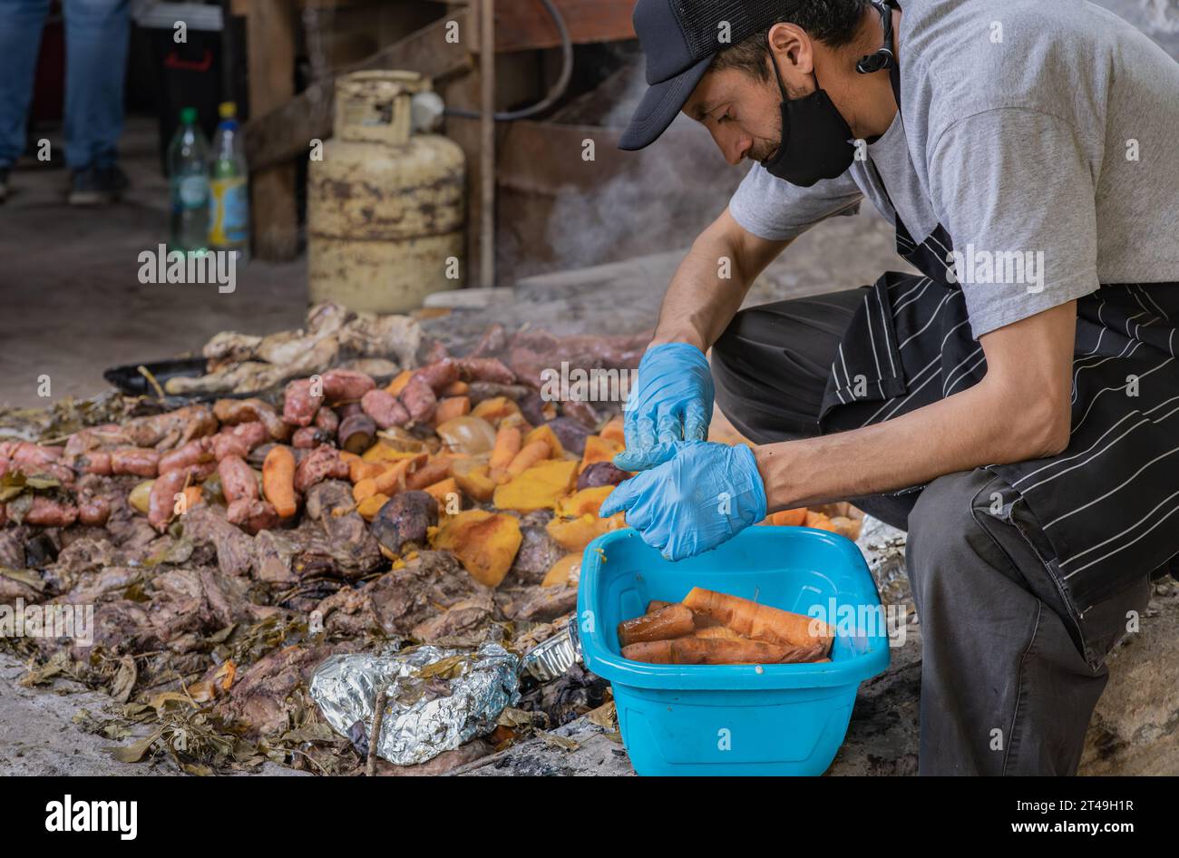 COLONIA SUIZA, SAN CARLOS DE BARILOCHE, ARGENTINA - 10 NOVEMBRE 2021: Un uomo mette da parte verdure preparate sottoterra come parte della cerimonia del curan Foto Stock