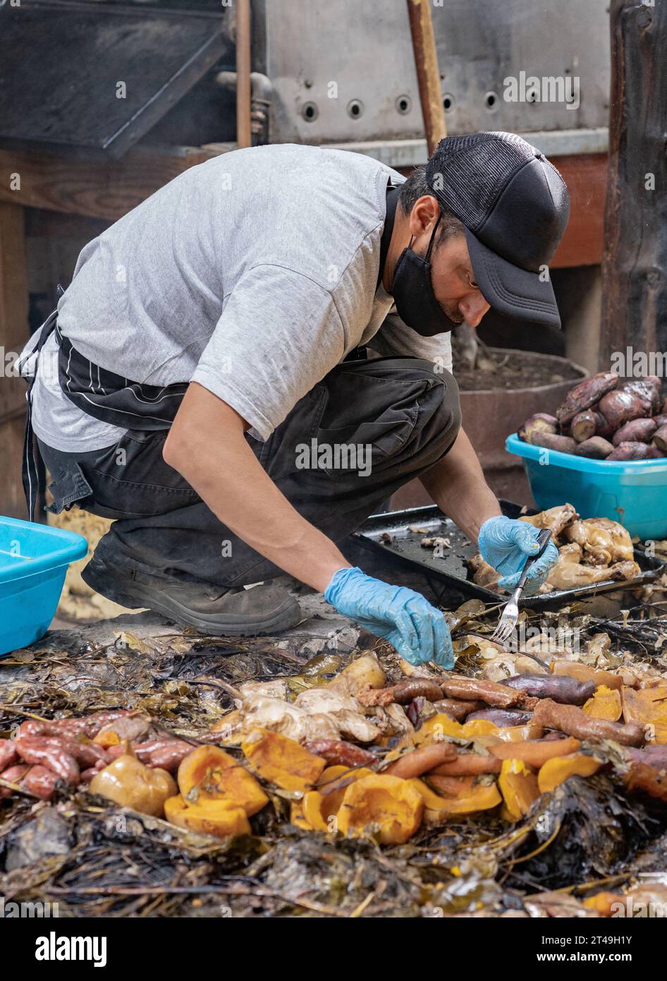 COLONIA SUIZA, SAN CARLOS DE BARILOCHE, ARGENTINA - 10 NOVEMBRE 2021: Un cuoco mette da parte le verdure e la carne preparate sottoterra come parte del Foto Stock