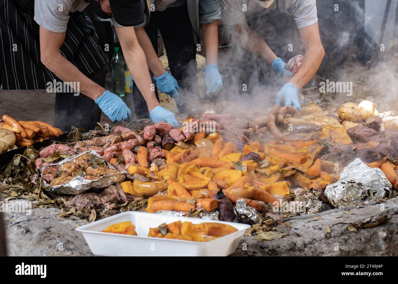 Un gruppo di cuochi mette da parte la carne e le verdure preparate sottoterra come parte della cerimonia del curanto. Colonia Suiza, Bariloche, Argentina. Foto Stock