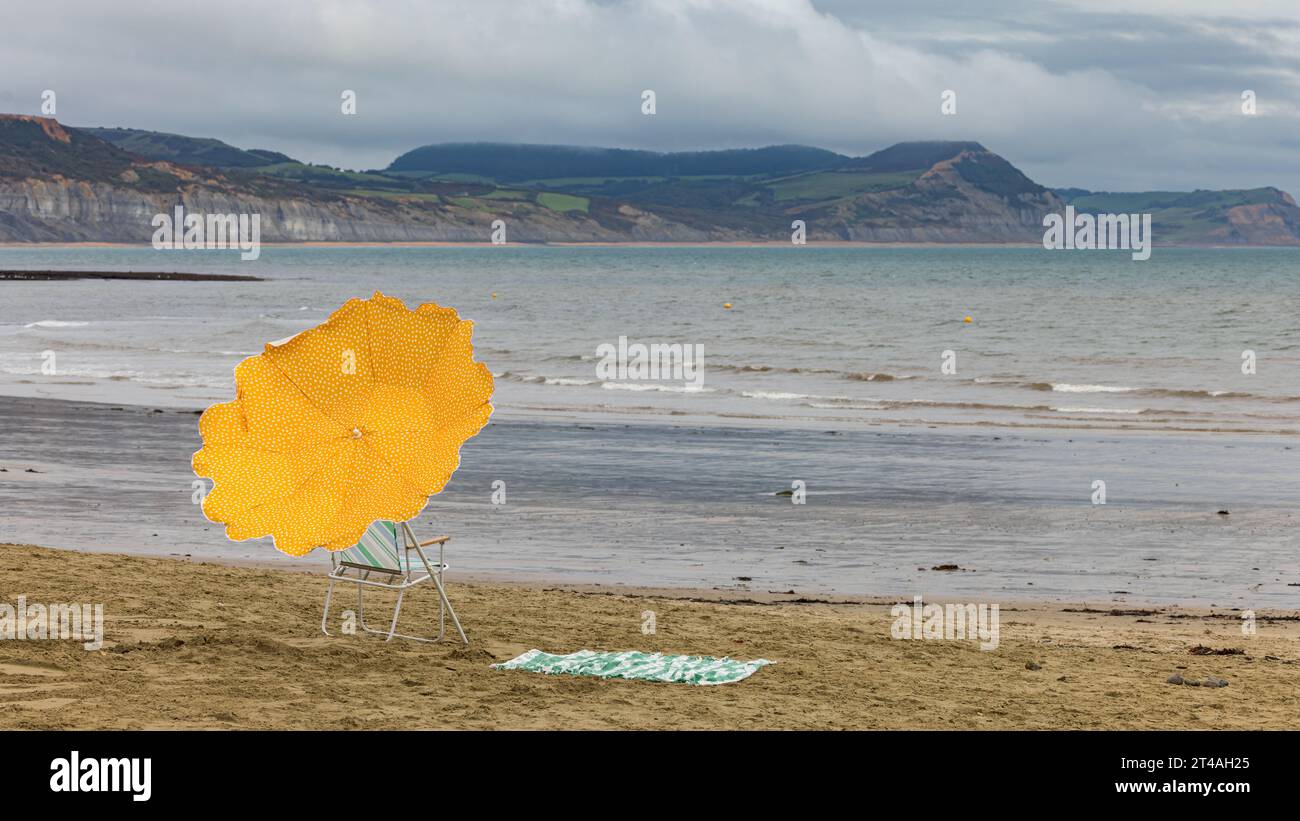 Ombrellone giallo sulla spiaggia di Lyme Regis, Dorset, Regno Unito Foto Stock