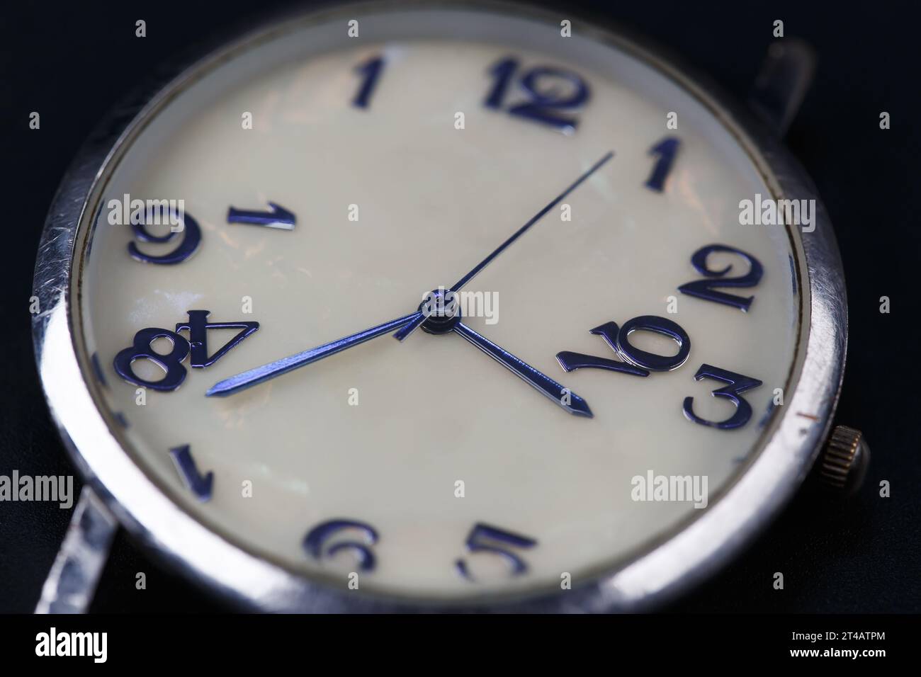 Il quadrante di un orologio da polso con lancette blu e numeri crollanti. Fotografia macro. Concetto di tempo che passa, invecchiamento Foto Stock