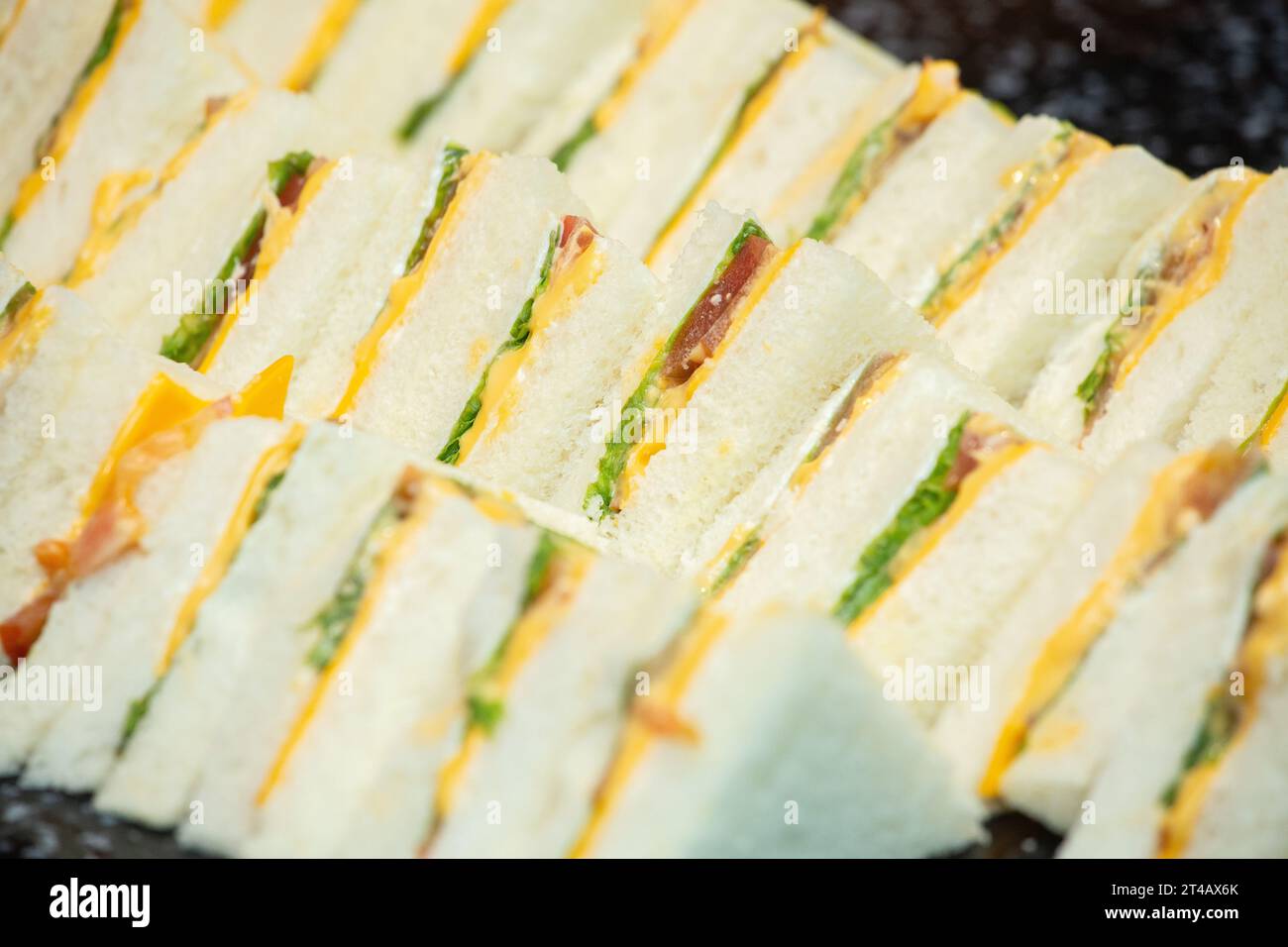 Primo piano di piccoli tagli di pomodoro e lattuga con sandwich al formaggio appena fatto. Foto Stock