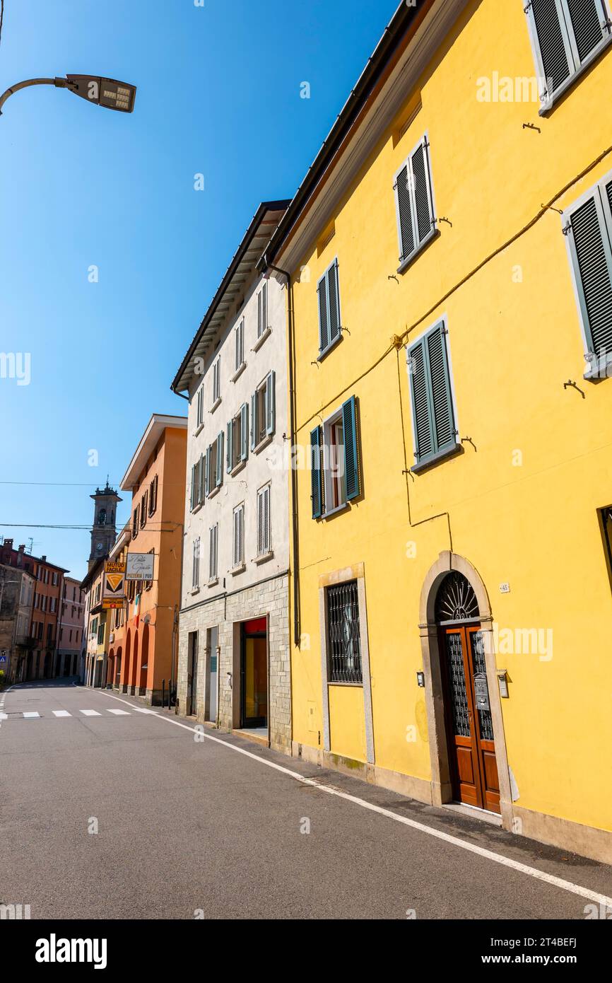 City Street a Porto Ceresio e Torre della Chiesa in una soleggiata giornata estiva a Porto Ceresio, Lombardia, Italia Foto Stock