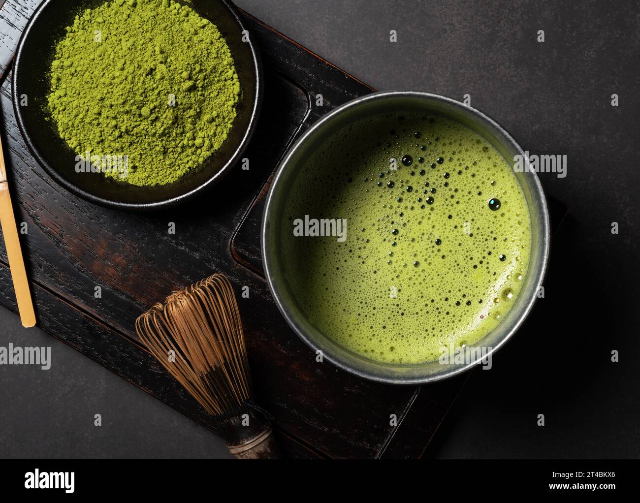 Polvere di Matcha e tè verde su sfondo scuro. Chasen (frusta per tè). Vista dall'alto. Foto Stock