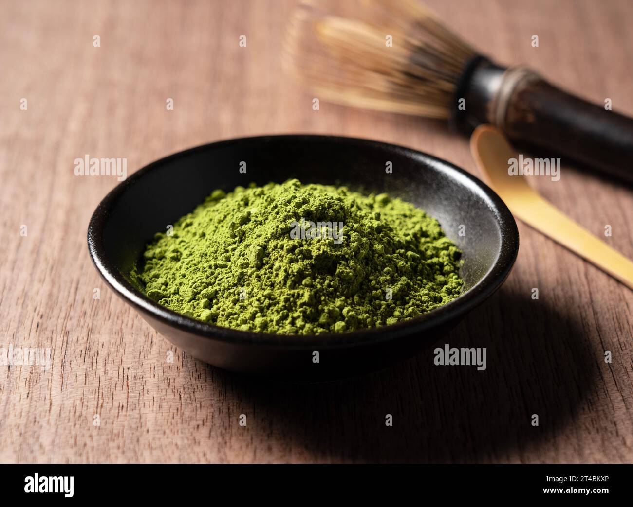 Matcha e Chasen su sfondo di legno. Polvere Matcha. Foto Stock