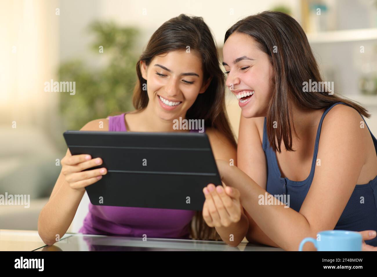 Donne felici che usano un tablet ridendo a casa Foto Stock