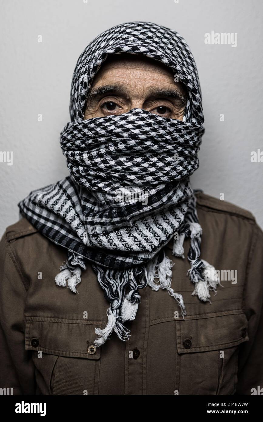 Ritratto di un militare che indossa un velo palestinese o uno shemagh, che ricopre il suo volto, su sfondo bianco. Concetto di miliziano, terrorismo, guerra, pale Foto Stock