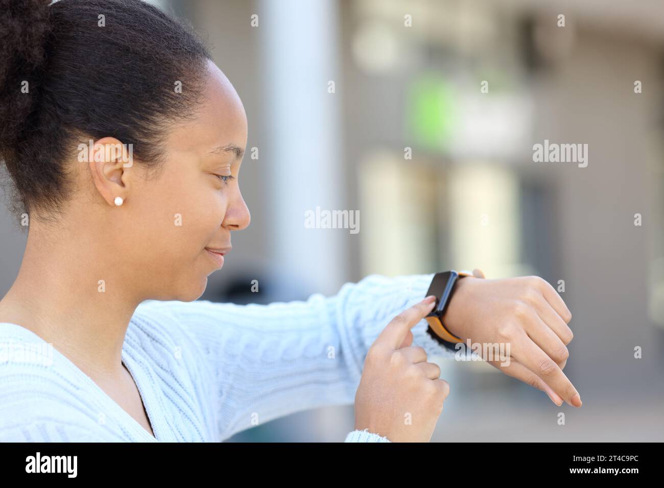 Donna nera che controlla uno smartwatch all'aperto in strada Foto Stock