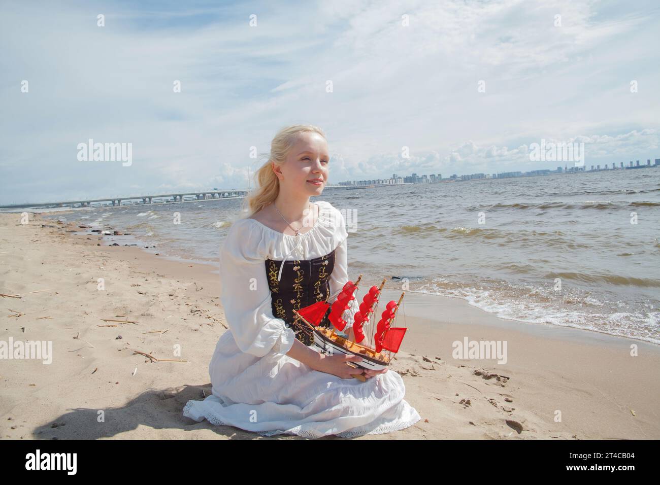 Giovane bella donna seduta sulla spiaggia del mare Foto Stock
