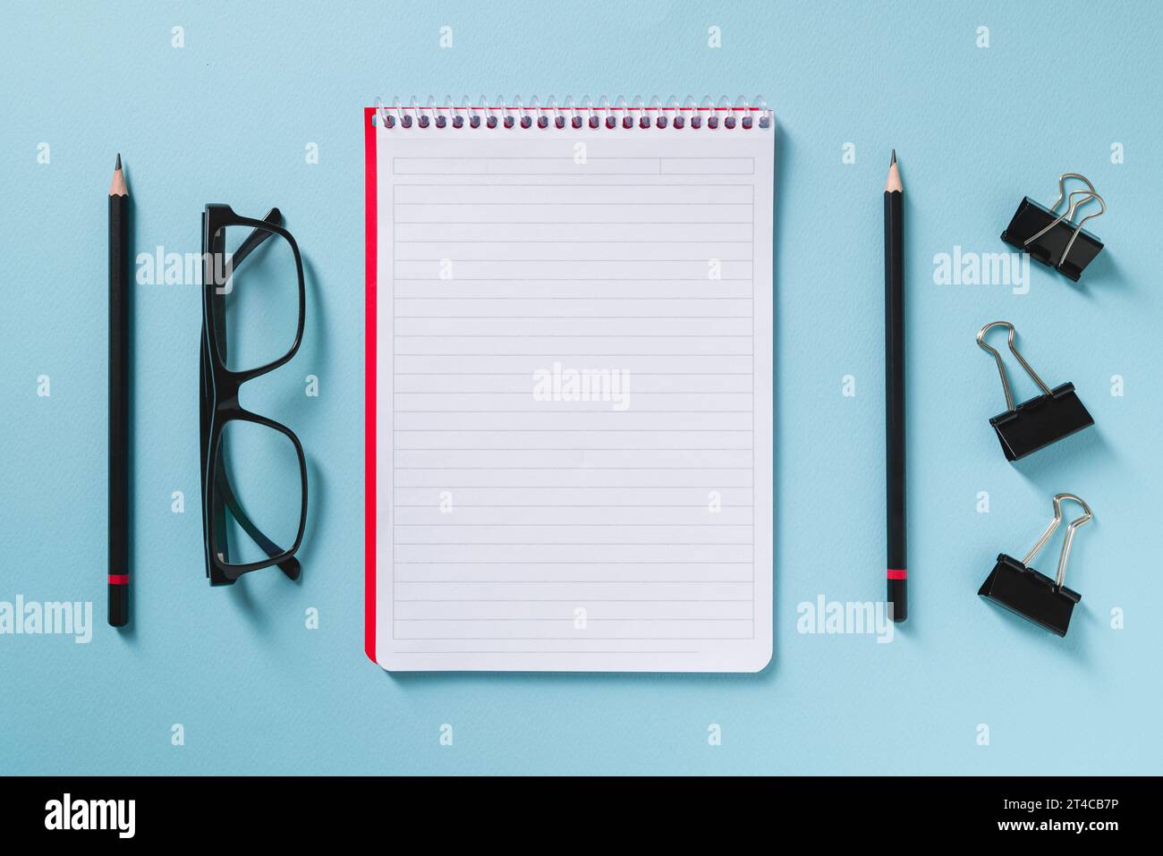 Vista dall'alto del notebook vuoto, degli occhiali e della penna sulla scrivania blu dell'ufficio Foto Stock