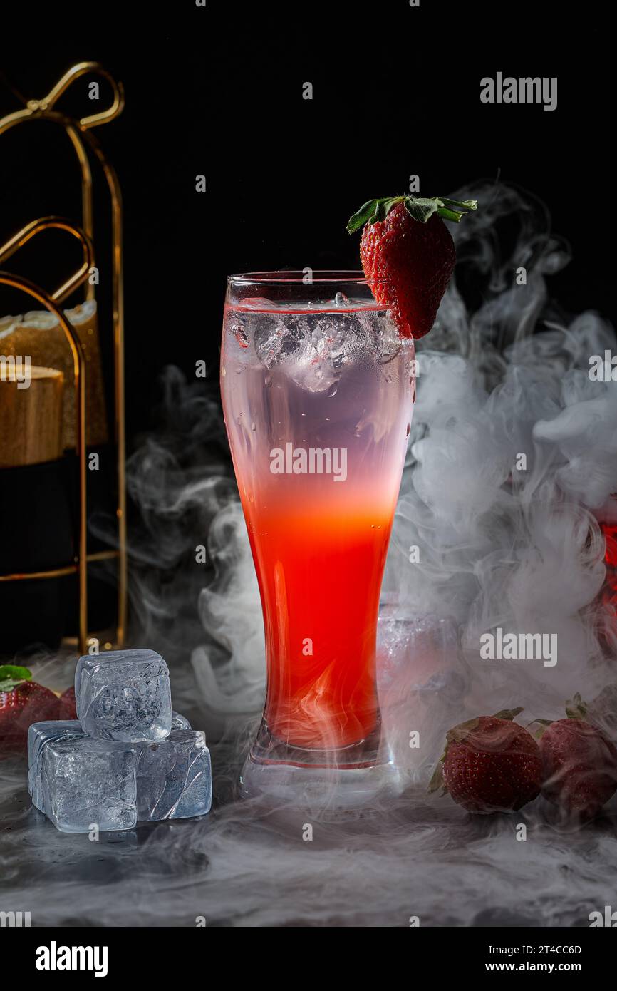 Immagine di un bicchiere di mojito al gusto di fragola su sfondo nero con effetti di fumo Foto Stock