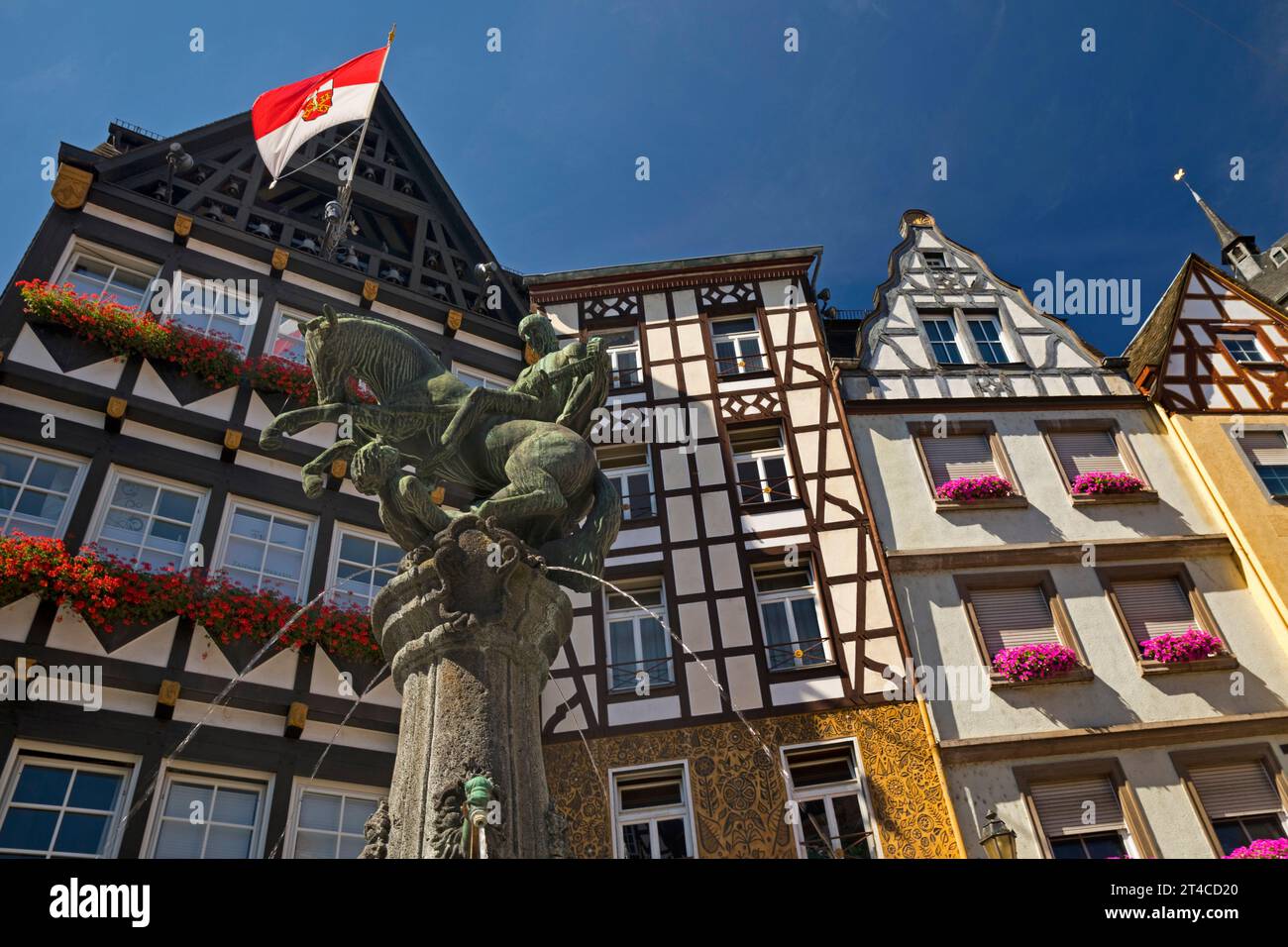 Fontana sulla piazza del mercato con case in legno e bandiera con stemma della città, Germania, Renania-Palatinato, Cochem Foto Stock
