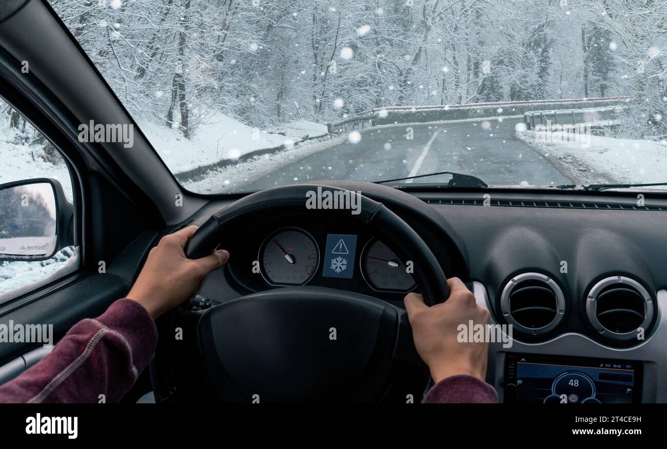 Un uomo sta guidando un'auto su una strada invernale in una tormenta. Foto Stock