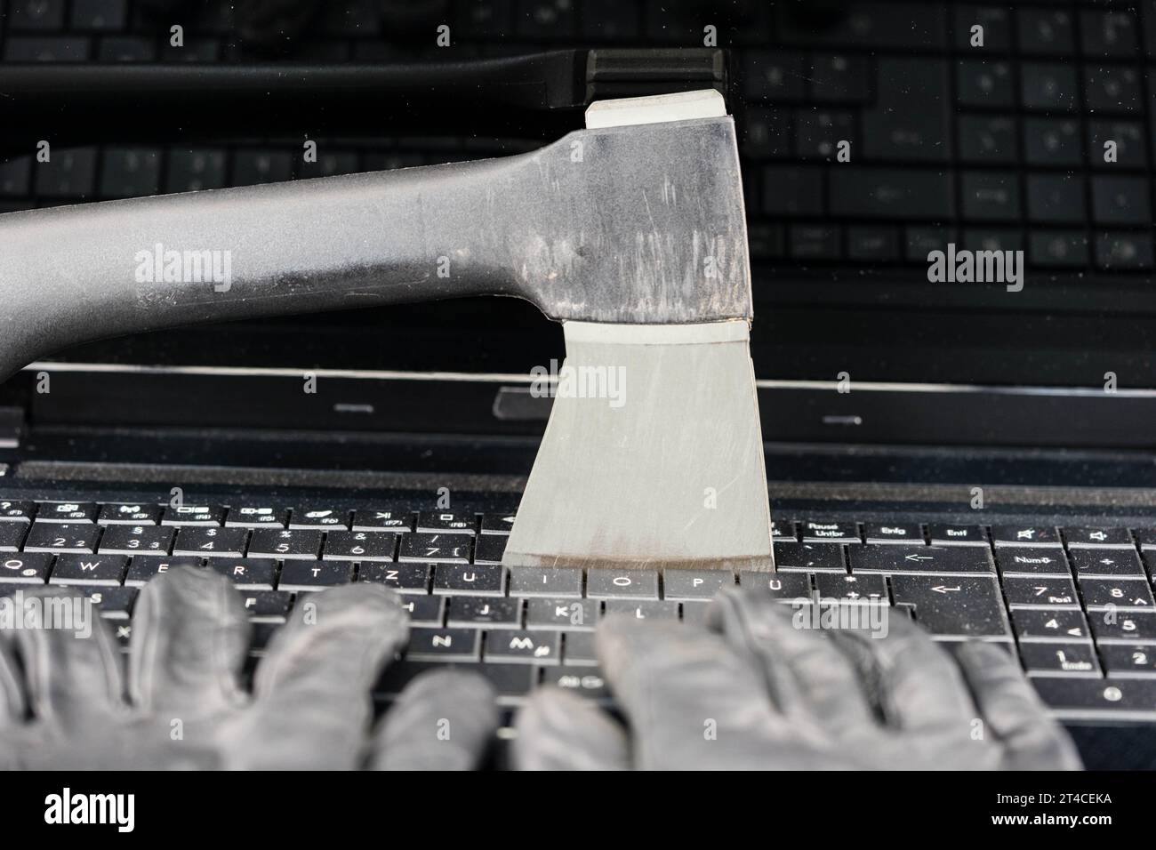 mani con guanti che digitano sulla tastiera del computer portatile con ascia, contaminazione dei dati Foto Stock