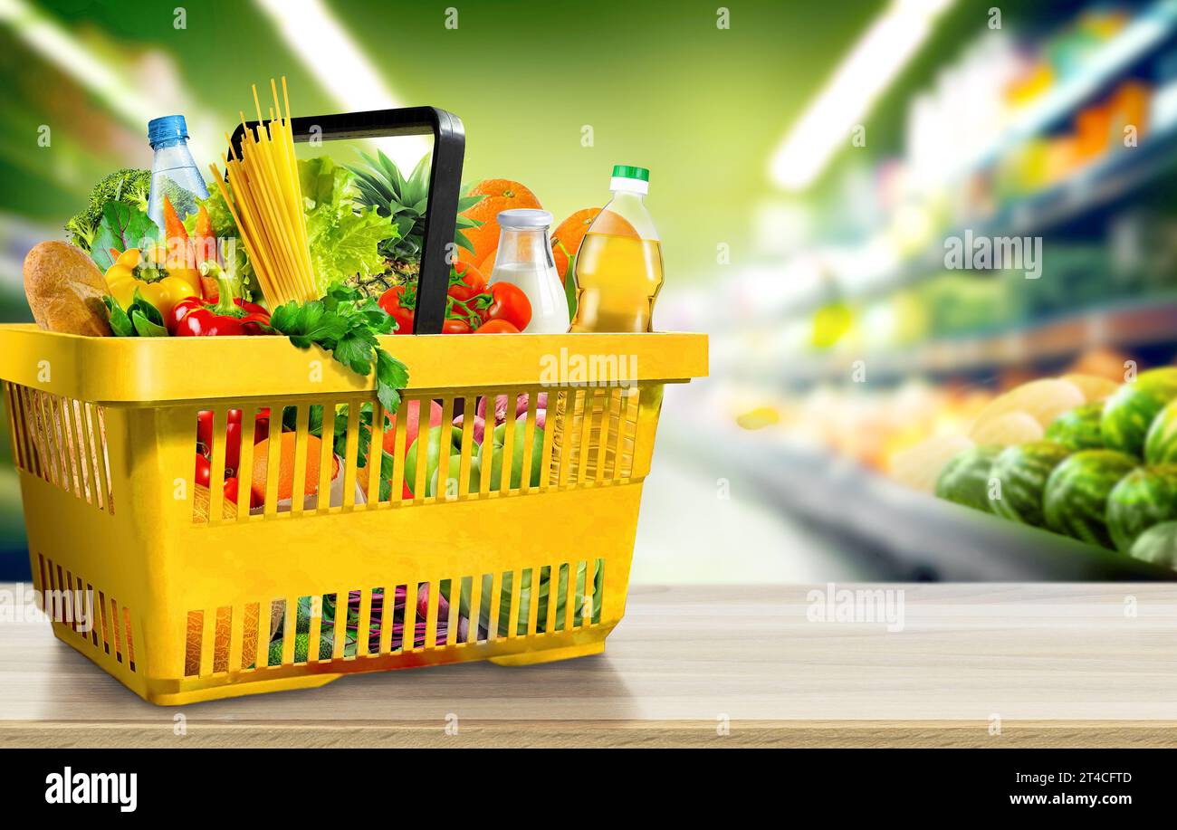 Cibo e generi alimentari nel cestino della spesa su un tavolo di legno sullo sfondo sfocato della corsia del supermercato Foto Stock