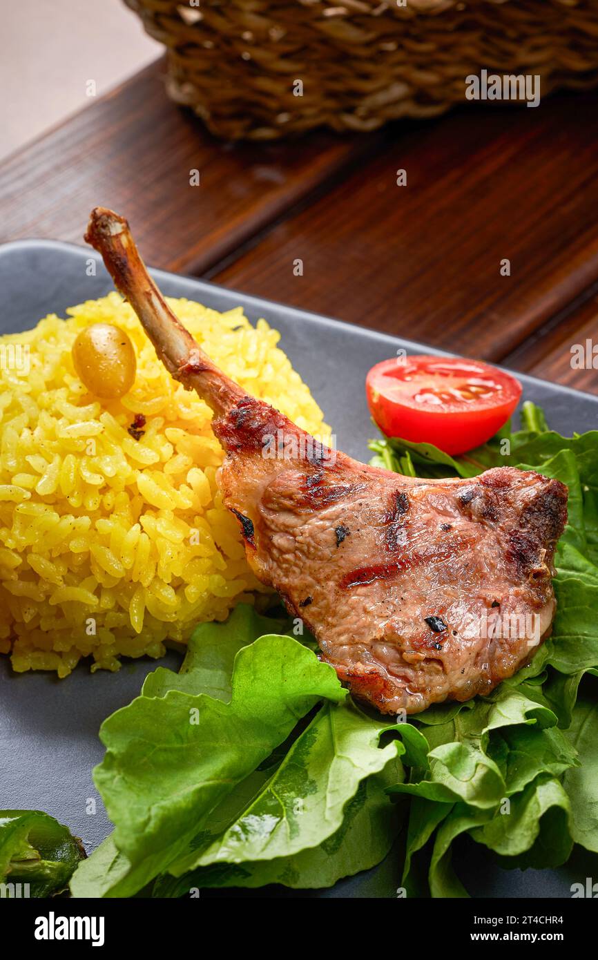 Una foto ravvicinata delle costolette di agnello alla griglia con riso e verdure a foglia Foto Stock