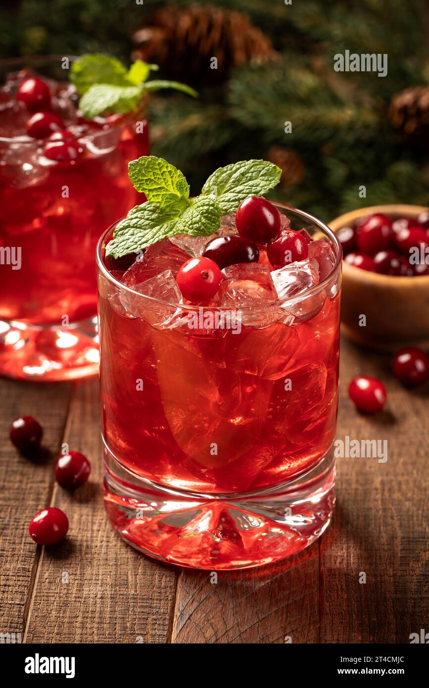 Cocktail di mirtilli rossi con mirtilli rossi freschi e foglie di menta su superficie di legno. Ramo di abete e coni di pino sullo sfondo Foto Stock