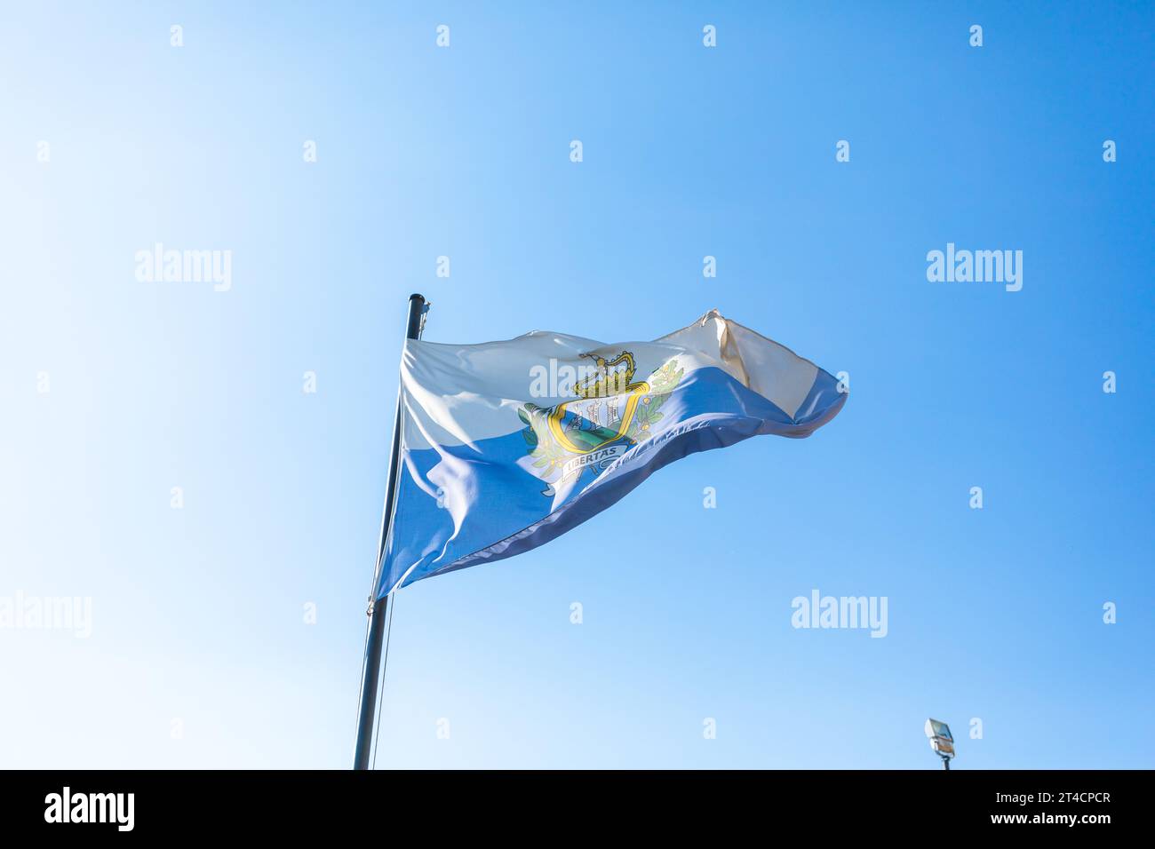 Bandiera di San Marino davanti al cielo blu che sbatte nel vento Foto Stock