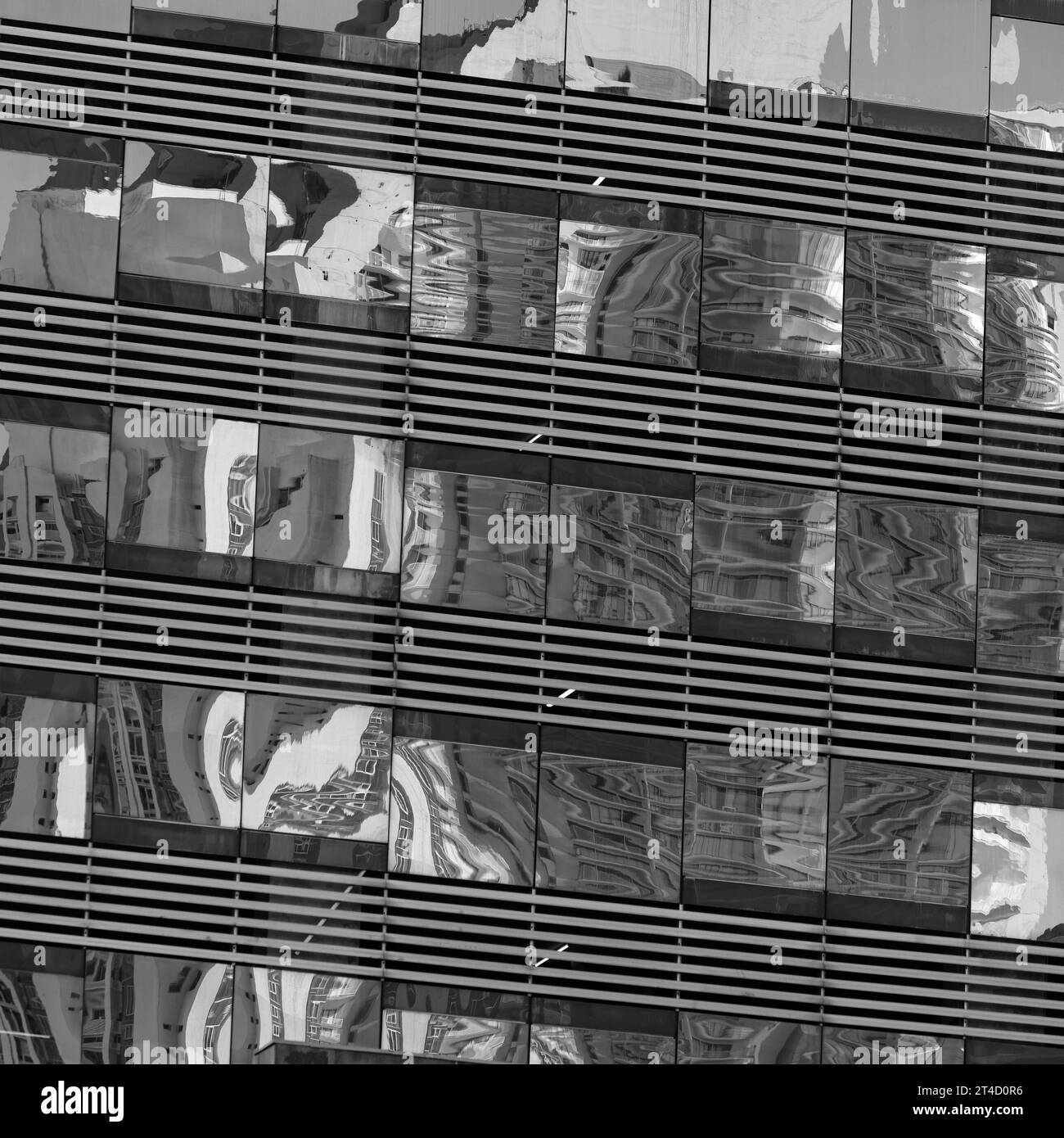 Un'accattivante cattura in bianco e nero che mostra i riflessi della città deformati e giustapposti all'interno delle linee strutturate della facciata di un edificio moderno Foto Stock