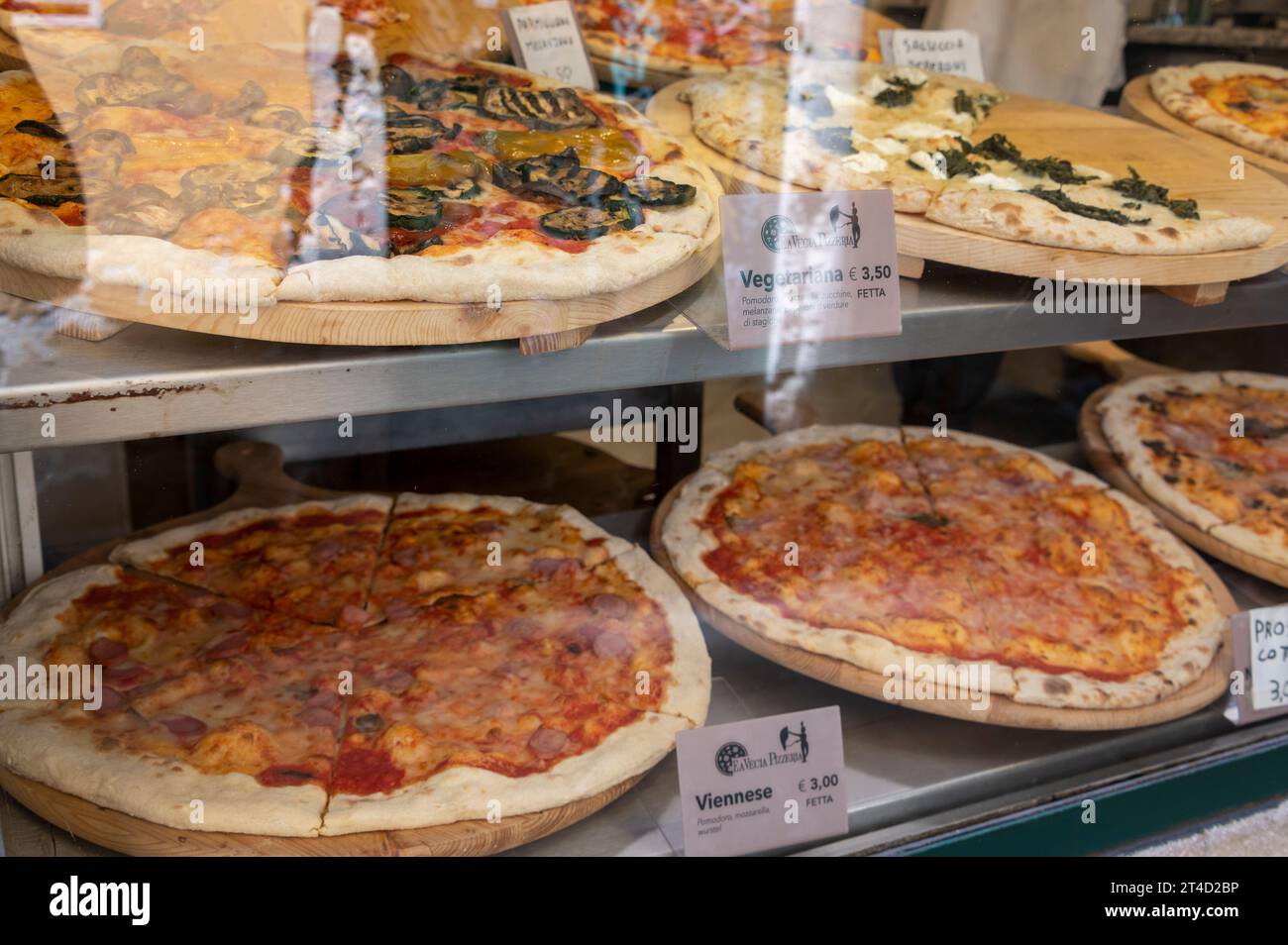 Una selezione di grandi pizze appena sfornate, ognuna con un nome, è in vendita in una vetrina di una pizzeria a Venezia, nella regione veneziana del nord Italia. Foto Stock