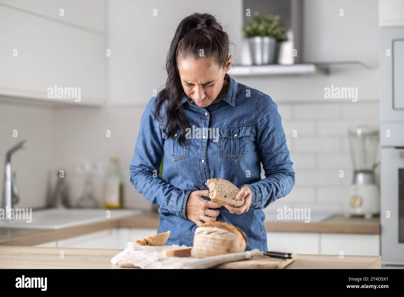 La donna non può mangiare pane e prodotti a base di cereali a causa dell'intolleranza al glutine. Una giovane celiaca soffre di dolore addominale dopo aver mangiato pane fresco. Foto Stock