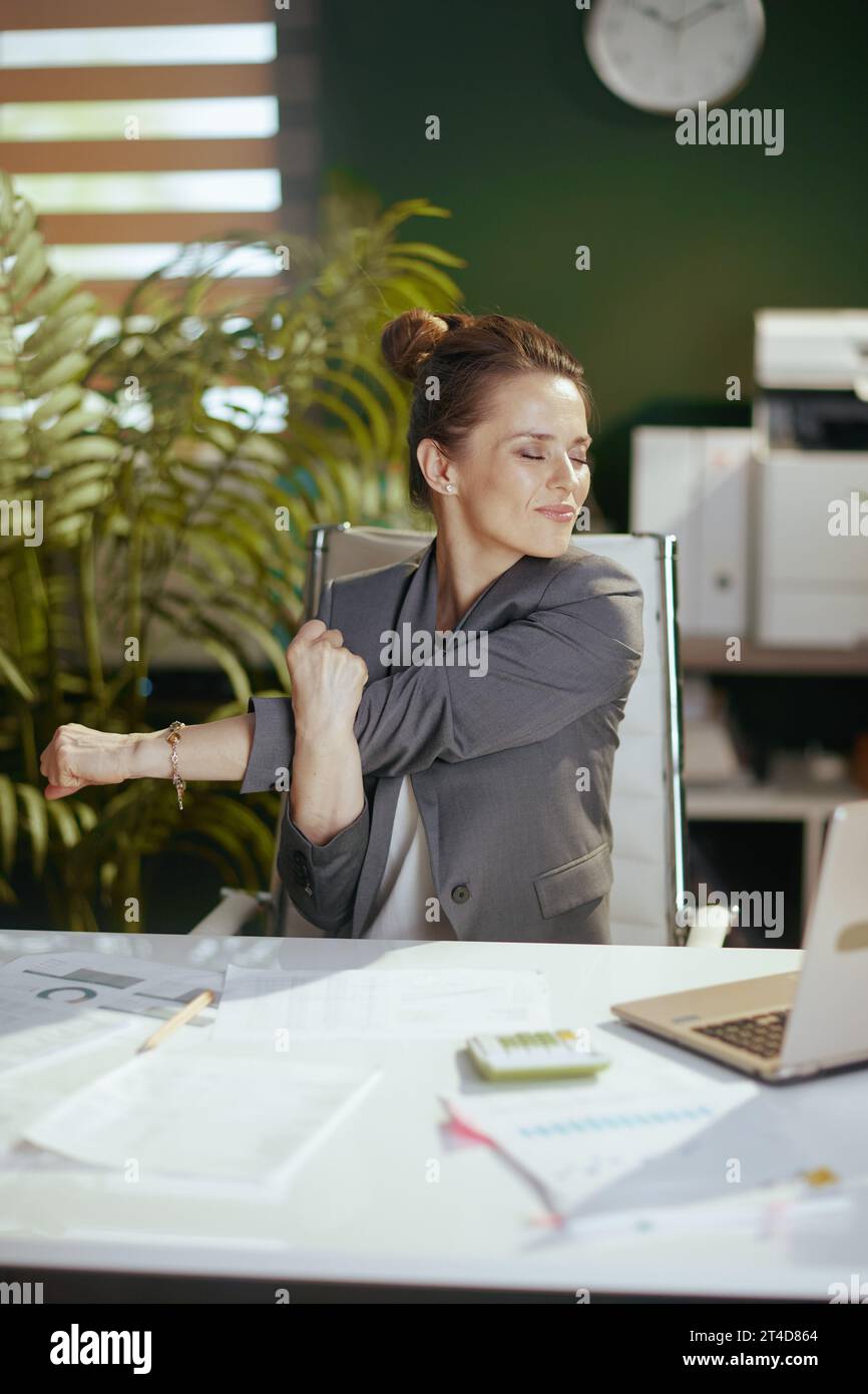 Ambiente di lavoro sostenibile. donna d'affari moderna sorridente in un moderno ufficio ecologico con un notebook che si allunga le mani. Foto Stock