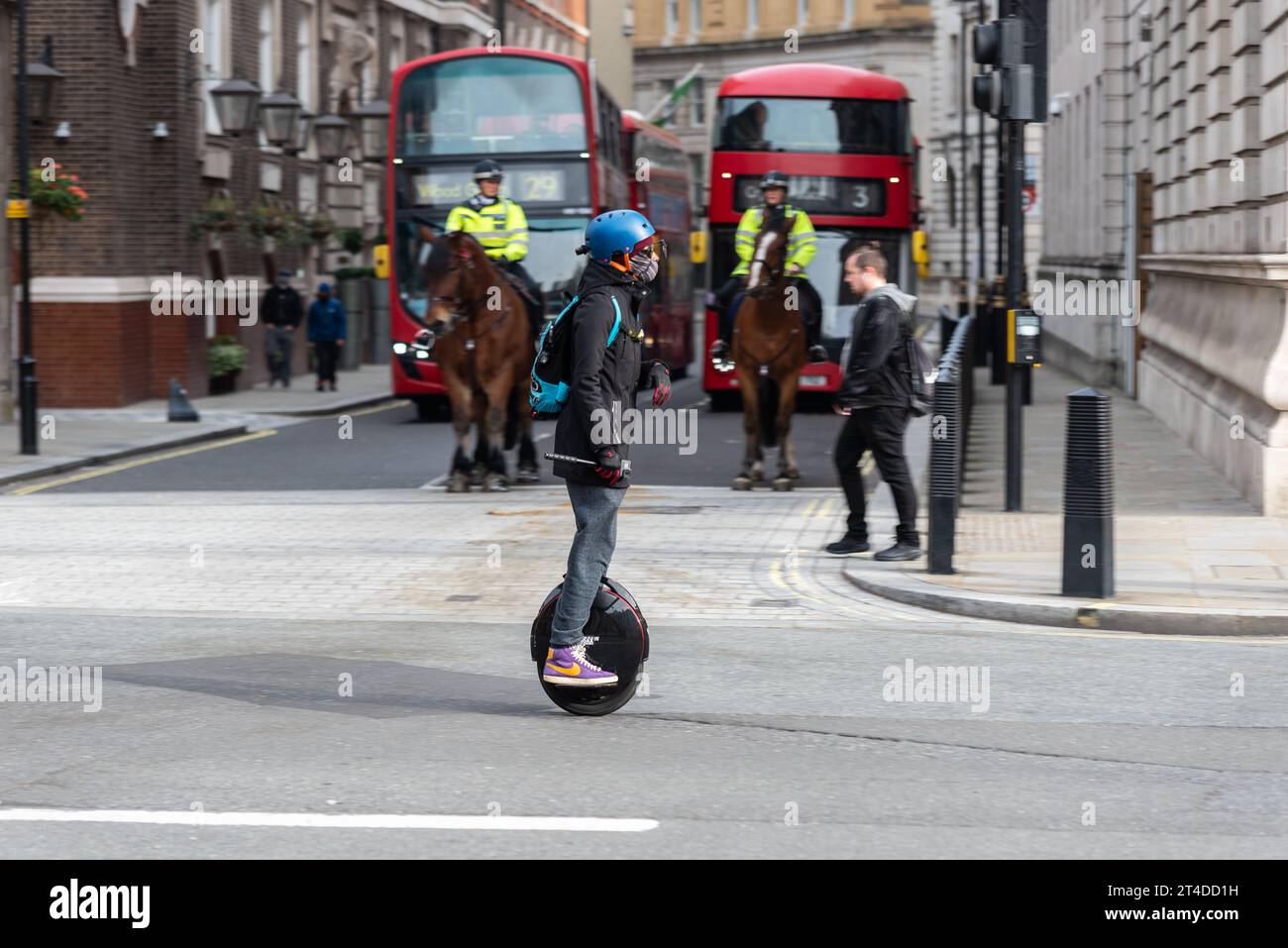 Pilota in sella a un uniciclo elettrico, un mezzo di trasporto personale autobilanciato con una sola ruota, a Londra durante il blocco Covid 19. Su una strada tranquilla Foto Stock