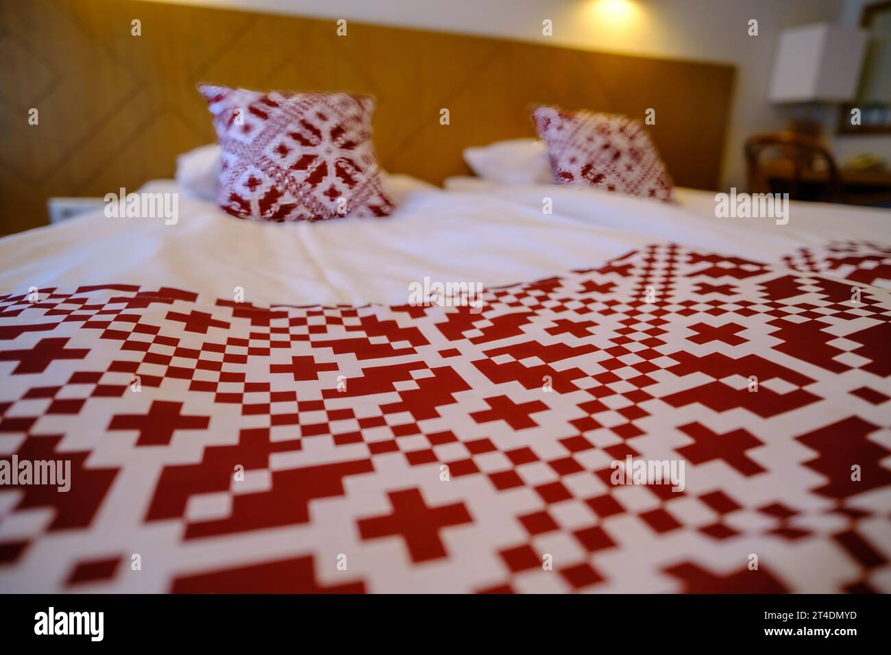 Area ricreativa nell'hotel. Biancheria da letto con simboli nazionali rossi dell'Estonia Foto Stock