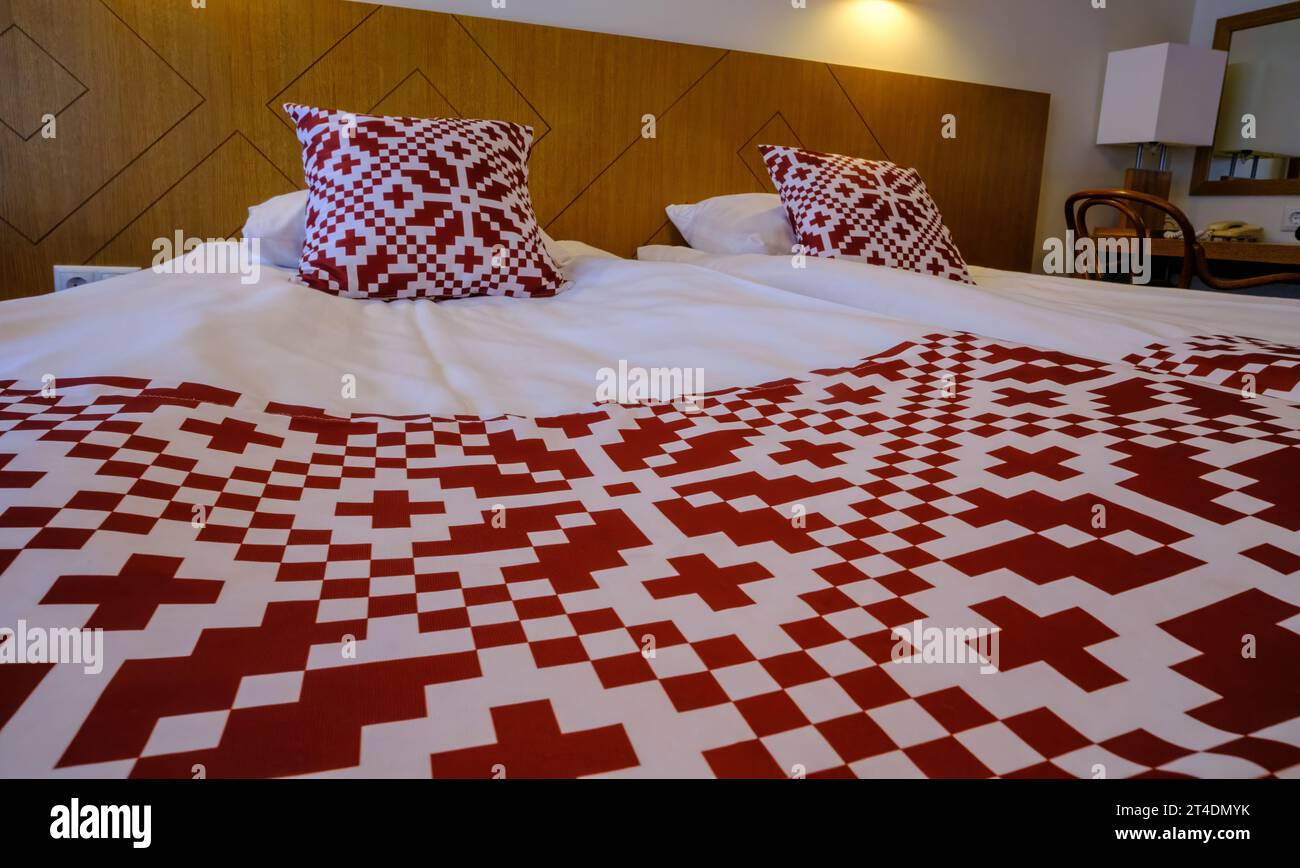 Area ricreativa nell'hotel. Biancheria da letto con simboli nazionali rossi dell'Estonia Foto Stock