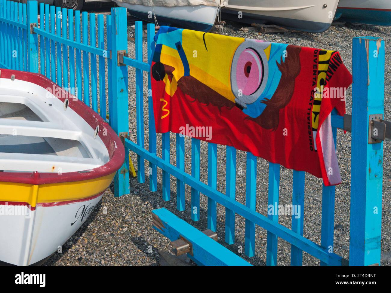Telo da spiaggia colorato appeso su recinzione accanto a un peschereccio, Cogoleto, Liguria, Italia Foto Stock