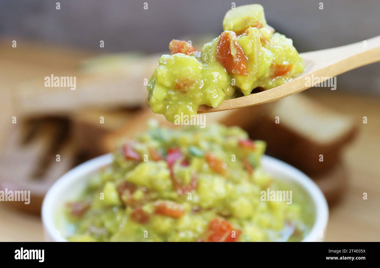 Primo piano del cucchiaio che raccoglie deliziosi guacamole appena fatti Foto Stock