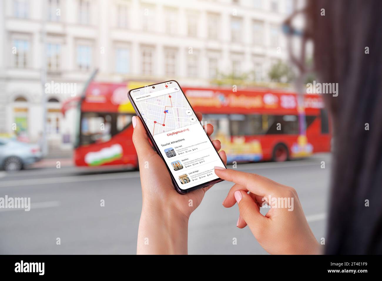 App City Sightseeing su smartphone in mani femminili. Autobus turistico cittadino sullo sfondo Foto Stock