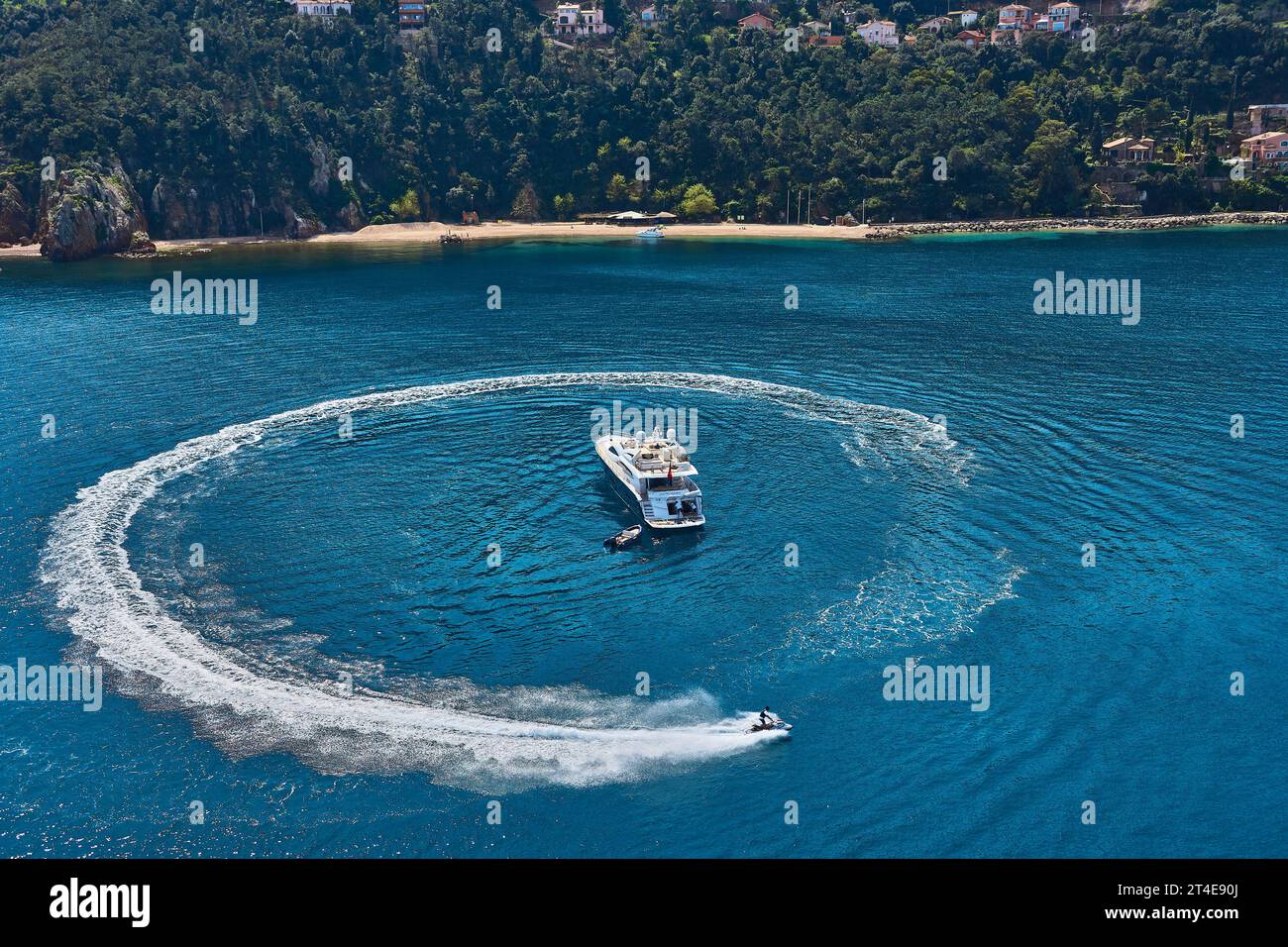 Foto aeree di uno yacht a motore ad Anchor in a Bay con un giro di moto d'acqua nel Mar turchese. Foto Stock