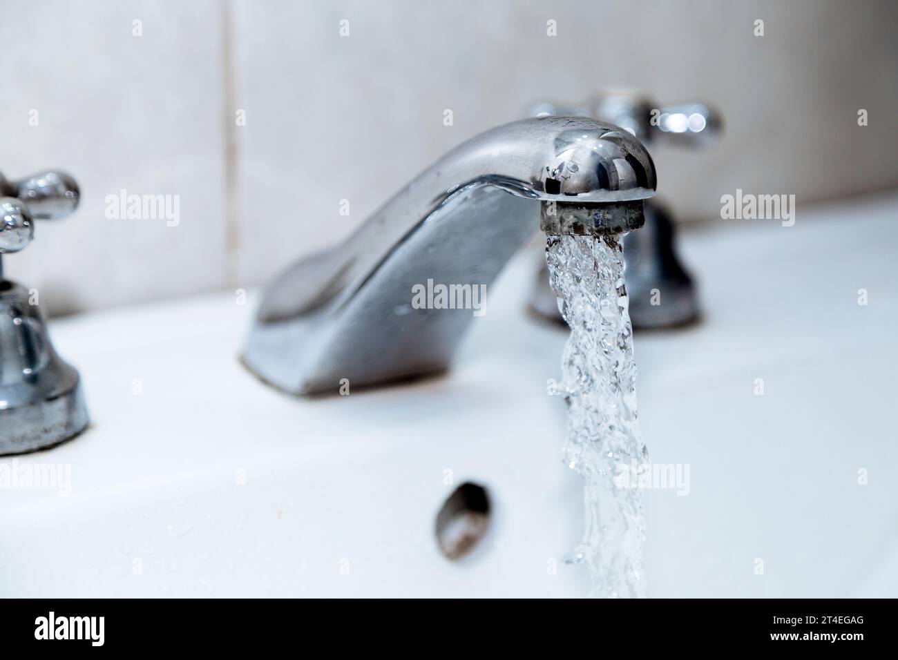 Rubinetto d'acqua in bagno. Rubinetto aperto con acqua corrente. Spreco di acqua potabile. Foto Stock