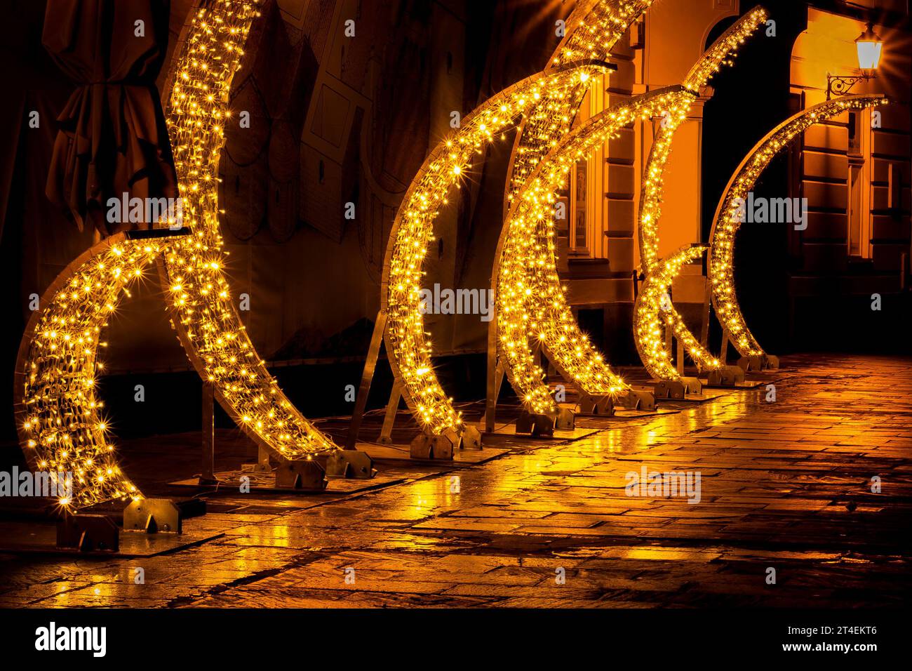 Una serie di luci di Natale gialle su una strada notturna della città dopo la pioggia Foto Stock