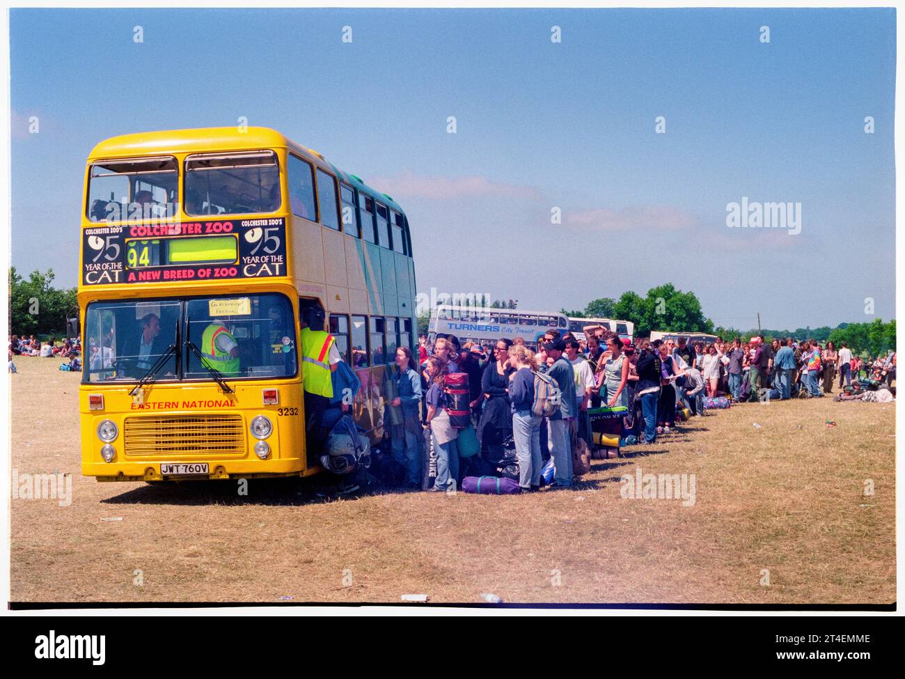 GLASTONBURY FESTIVAL, 1995: La gente fa la fila per il giro nell'area della "stazione degli autobus" nel parcheggio il lunedì mattina dopo la fine del Glastonbury Festival, Pilton Farm, Somerset, Inghilterra, 26 giugno 1995. Nel 1995 il festival ha celebrato il suo 25° anniversario. Non c'era nessuna fase piramidale quell'anno, dato che era bruciata. Foto: ROB WATKINS Foto Stock