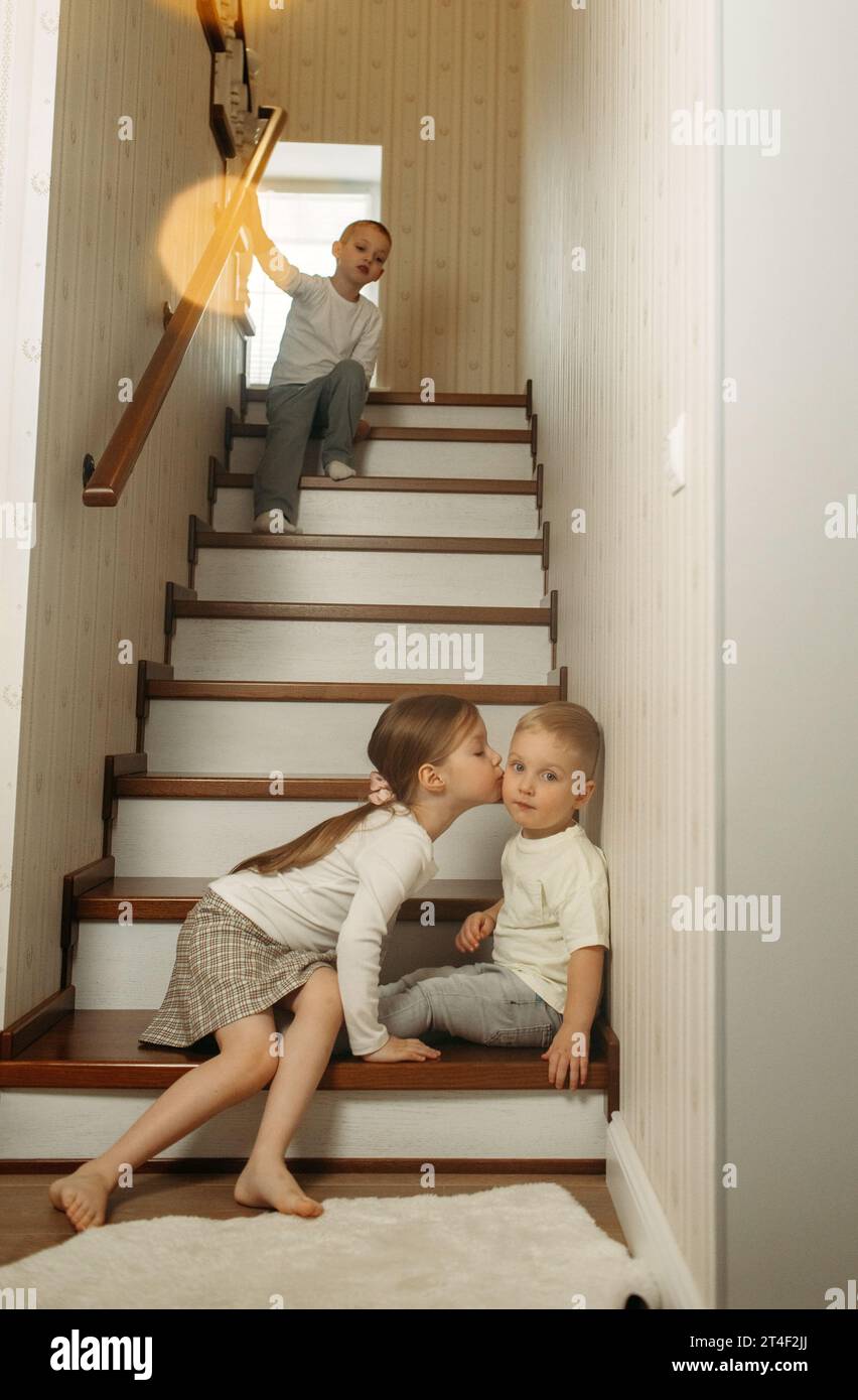 Due fratelli e sorelle sono seduti sulle scale in un'accogliente casa di legno. La vita in campagna. Foto Stock