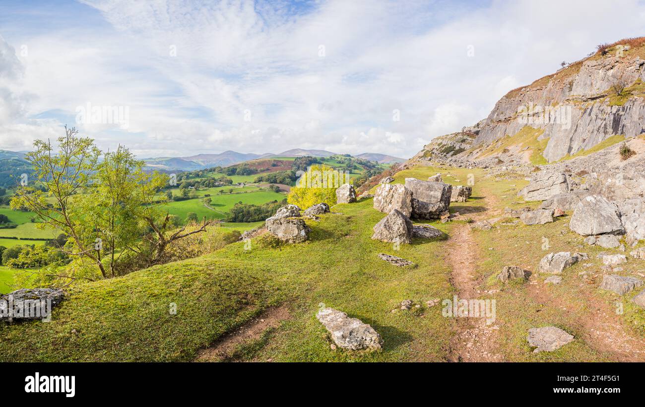 Un panorama multi immagine del sentiero Offas Dyke che serpeggia intorno a grandi massi ai piedi delle scogliere della catena montuosa Clwydian vicino a Llangollen. Foto Stock