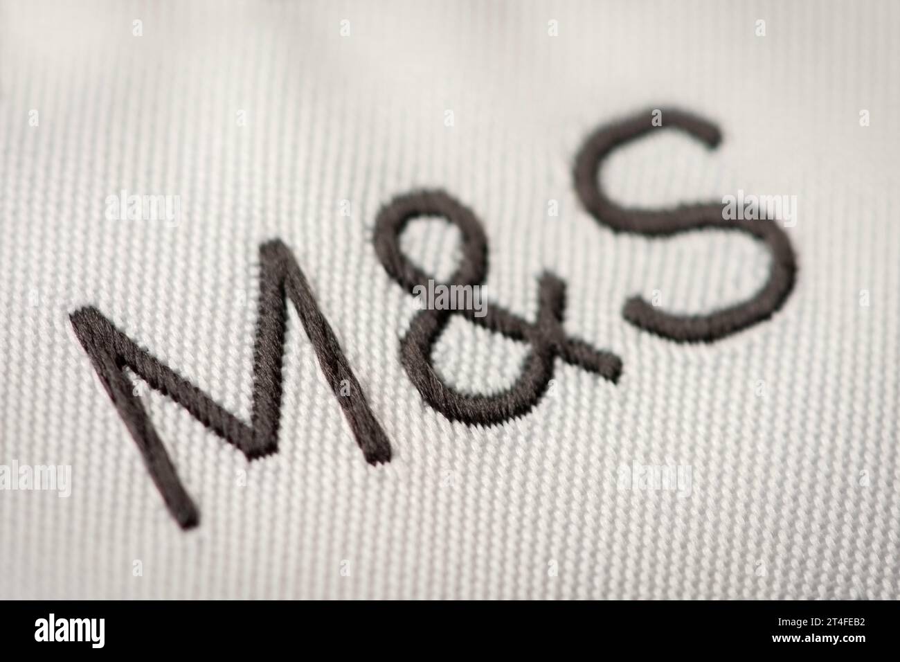 Un primo piano di un logo M&S ricamato come mostrato su un tag. Foto Stock