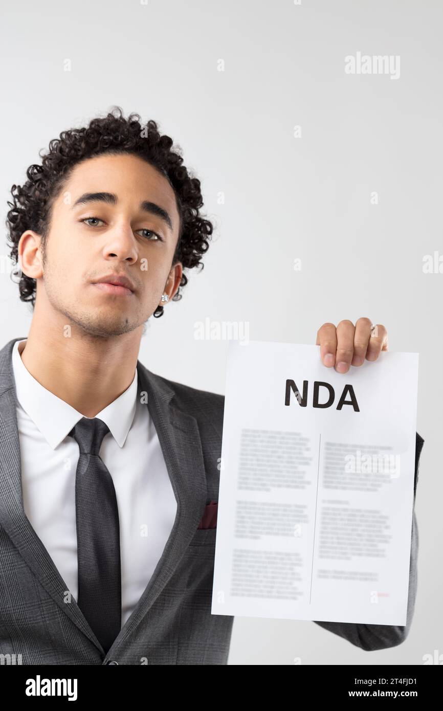 Indossando un abbigliamento professionale, la posa assertiva dell'uomo sottolinea il significato della "NDA" che presenta Foto Stock