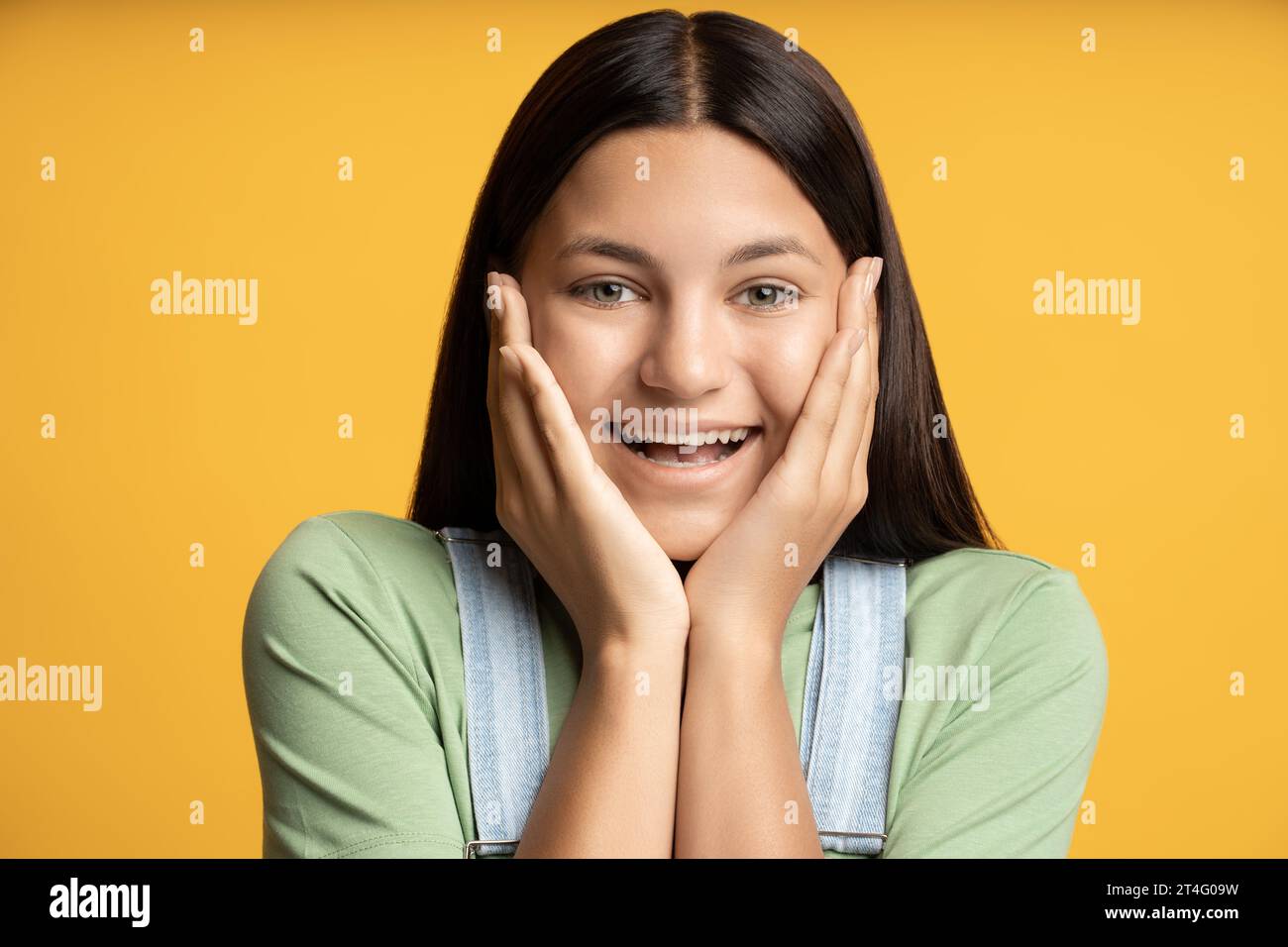 Ritratto in studio ha scattato una ragazza adolescente felice che guarda la fotocamera sorridente su sfondo giallo. Foto Stock