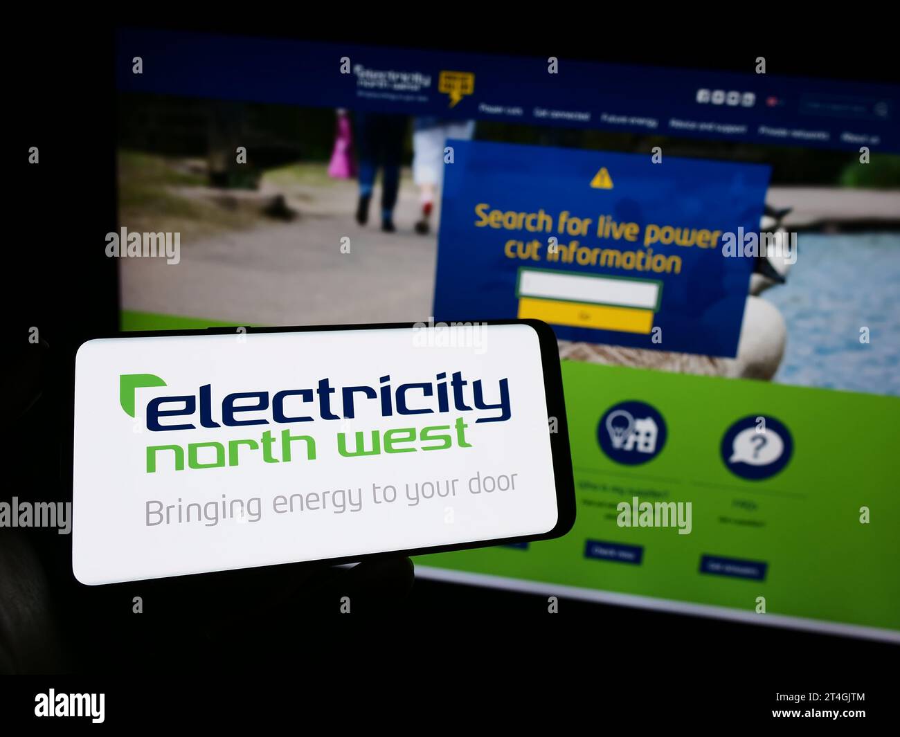 Persona che possiede un telefono cellulare con il logo della società energetica britannica Electricity North West Limited davanti alla pagina Web. Concentrarsi sul display del telefono. Foto Stock