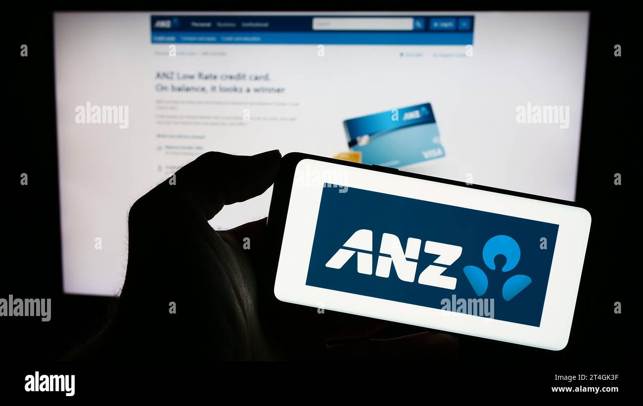 Persona che possiede uno smartphone con il logo di Australia e New Zealand Banking Group Limited (ANZ) davanti al sito Web. Concentrarsi sul display del telefono. Foto Stock