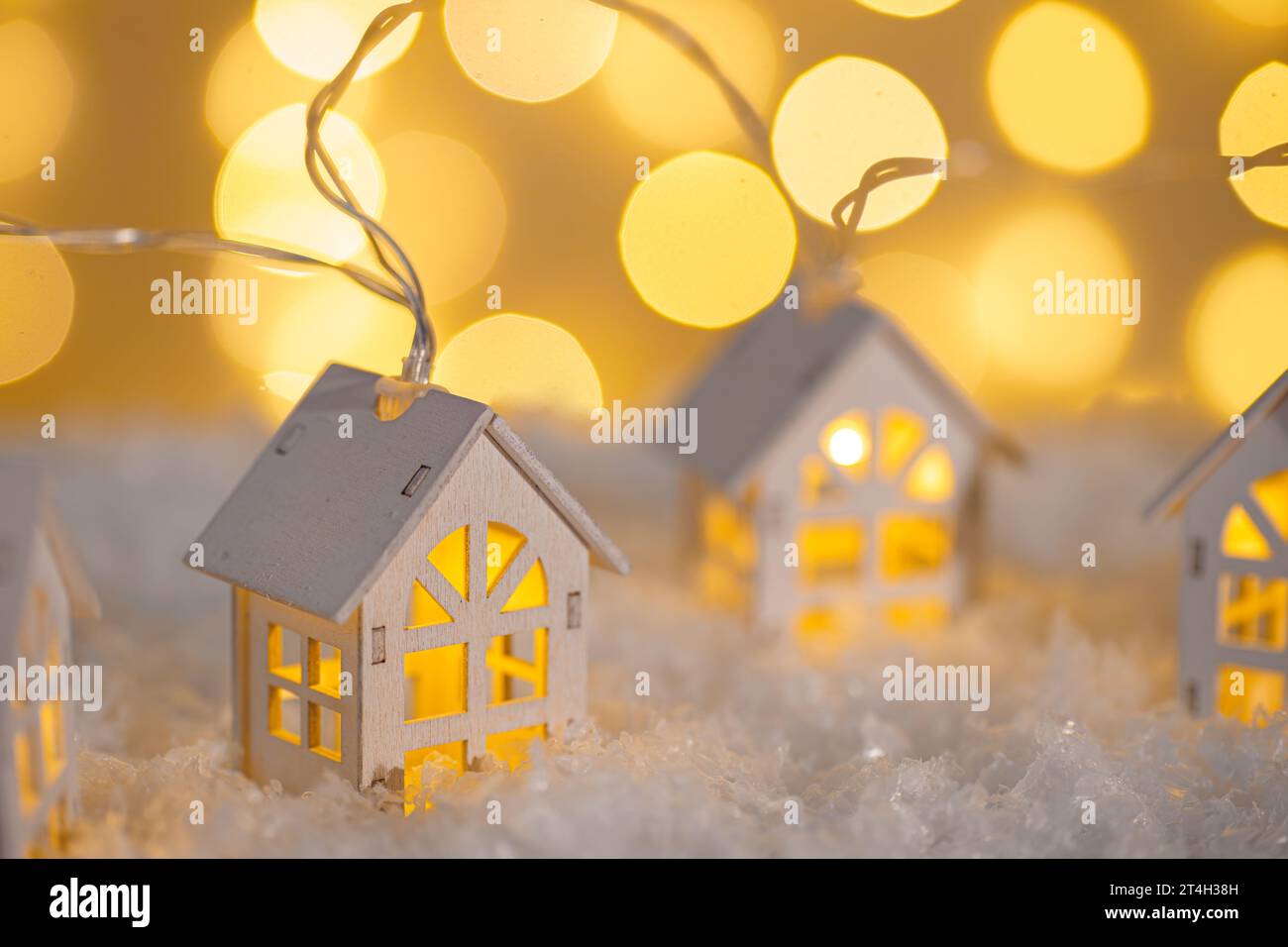 Case in legno, ghirlande di luci sulla neve e luci scintillanti su sfondo bokeh. Biglietto d'auguri per Natale e Capodanno con spazio per le copie. Illuminati per le vacanze Foto Stock