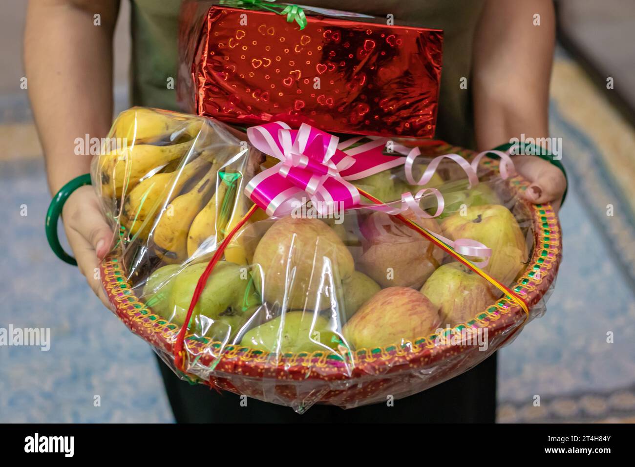 confezione regalo di frutta ripiena di frutta e confezione regalo che tiene a portata di mano da un angolo piatto Foto Stock