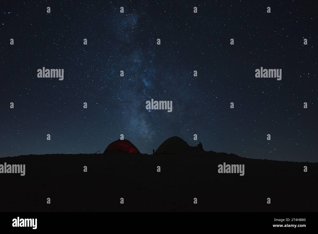 Campeggiare il cielo notturno della via Lattea sopra la silhouette delle tende Foto Stock