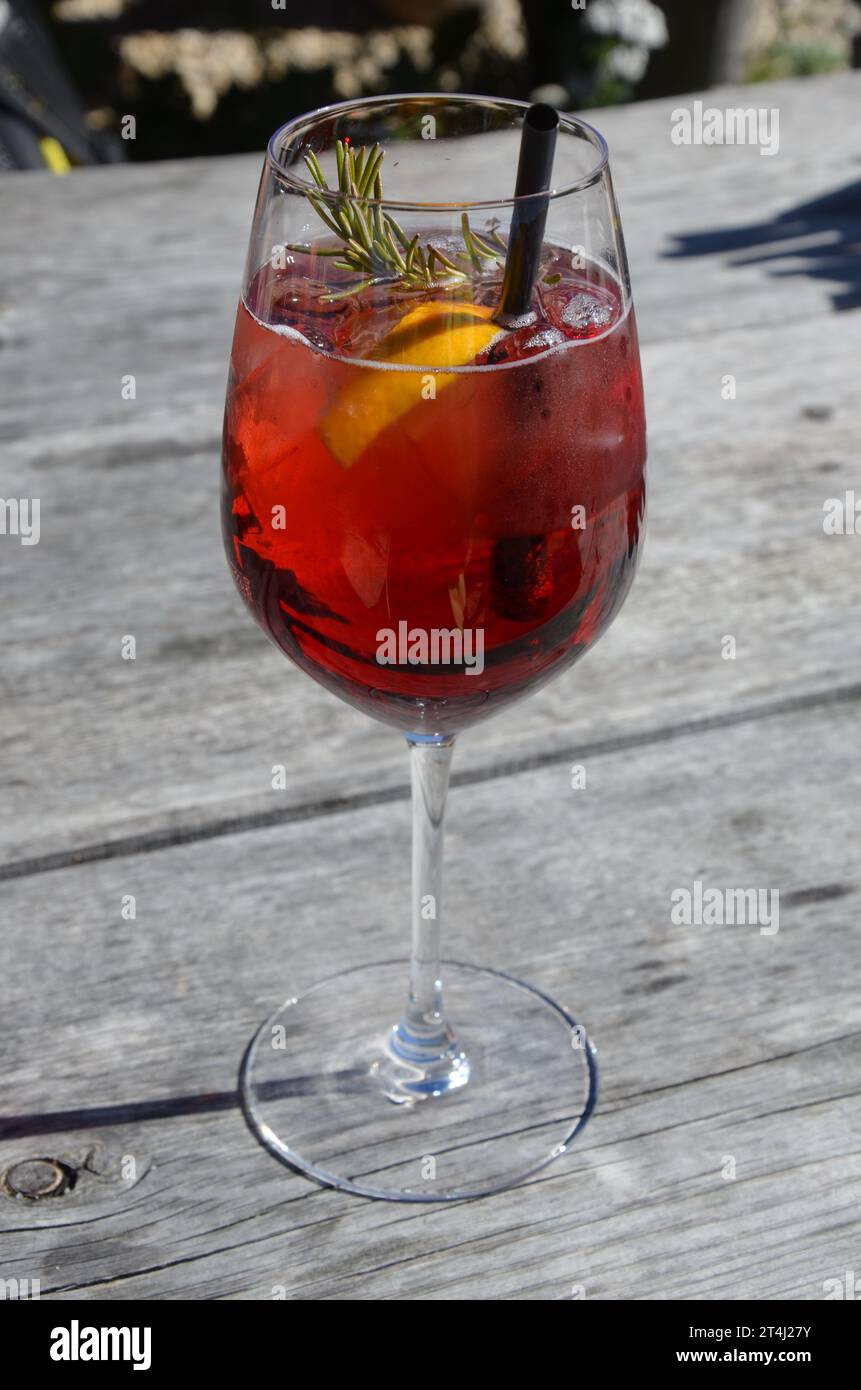 Cocktail rosso in un vetro cristallino con paglia, sfondo di legno sfocato Foto Stock