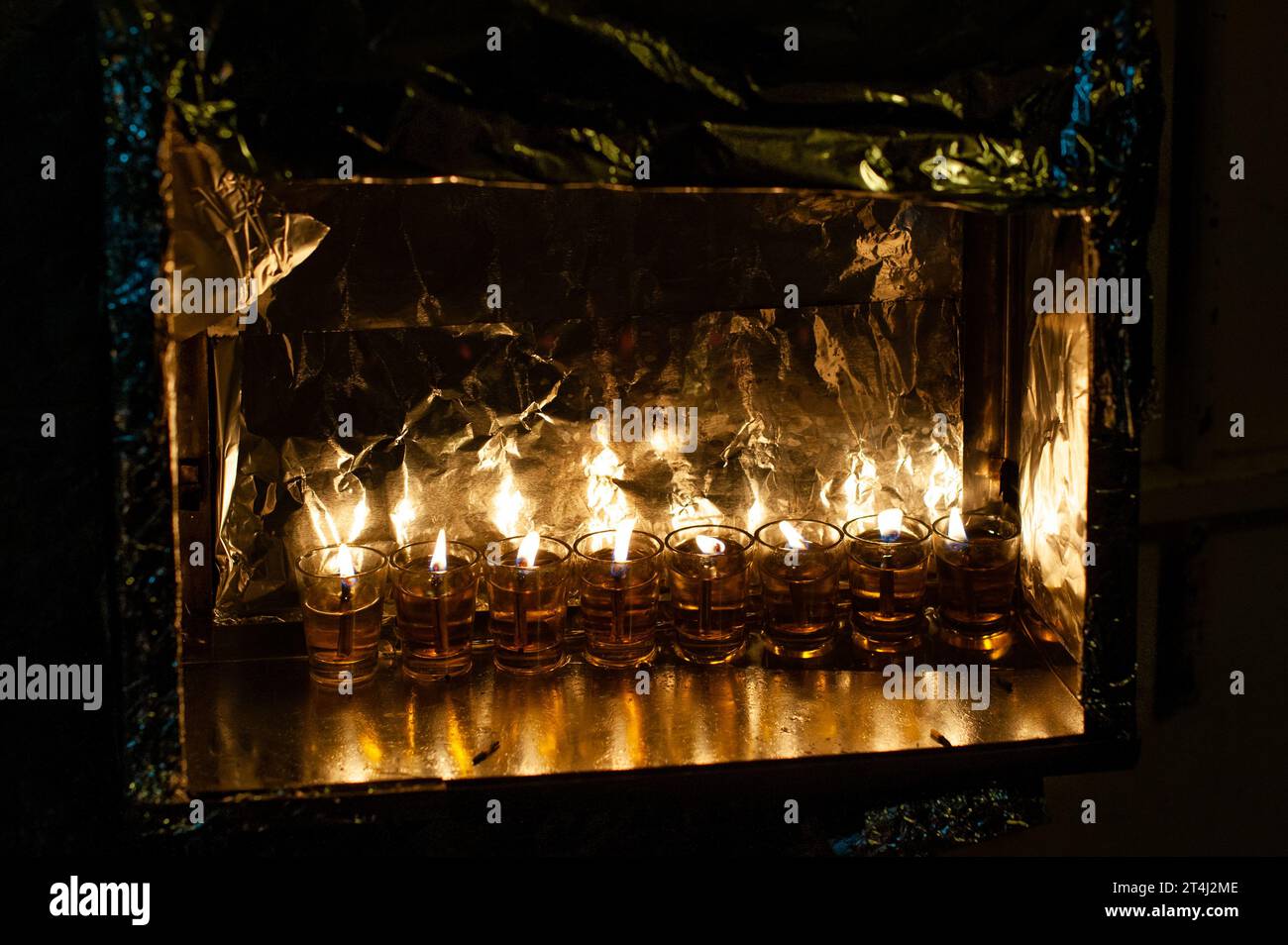 Le fiale di vetro contengono olio e stoppini brucianti in una menorah luminosa nell'ottava notte del festival ebraico di Hanukkah in Israele. Foto Stock